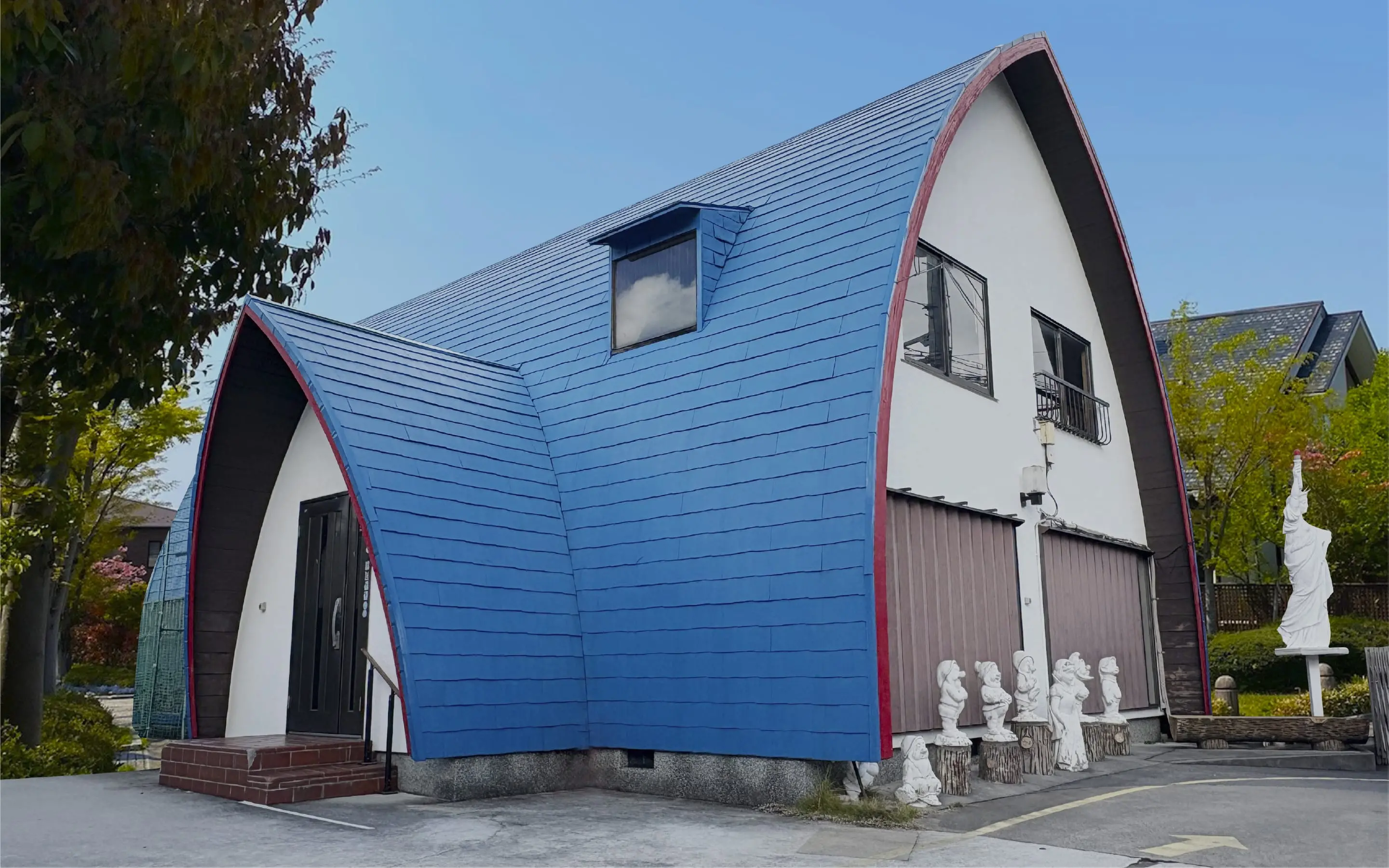 青い屋根と赤い縁取りが特徴的なユニークなデザインの建物外観